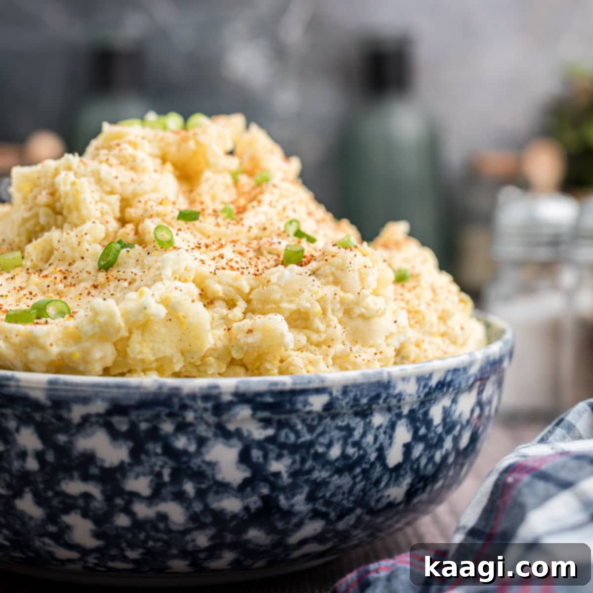 Elevate Your Plate with Essential Southern Sides 7 A close up image of a large bowl of creamy Cajun potato salad, generously sprinkled with fresh green onions.