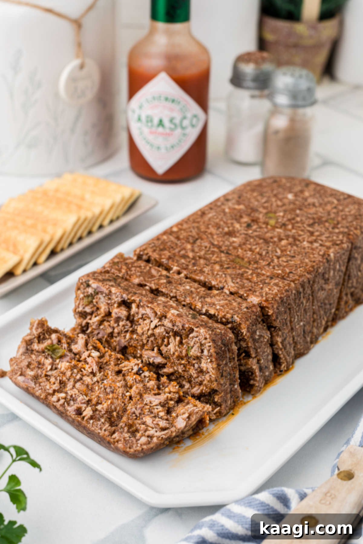 A beautifully formed loaf of mock hog head cheese, with several slices already cut and ready to serve.