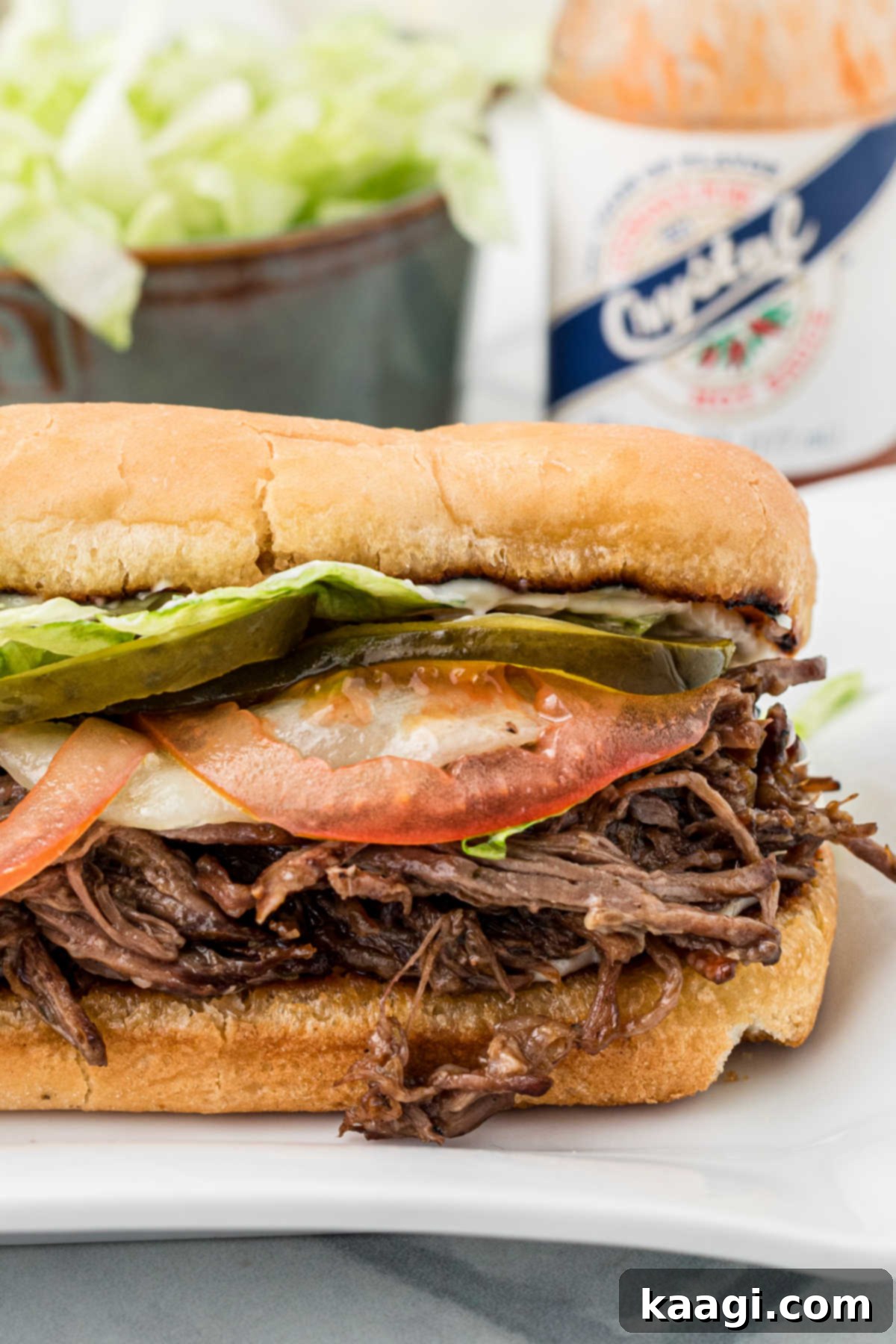 New Orleans Roast Beef Legend 2 A close up of a roast beef po boy with some hot sauce in the back.
