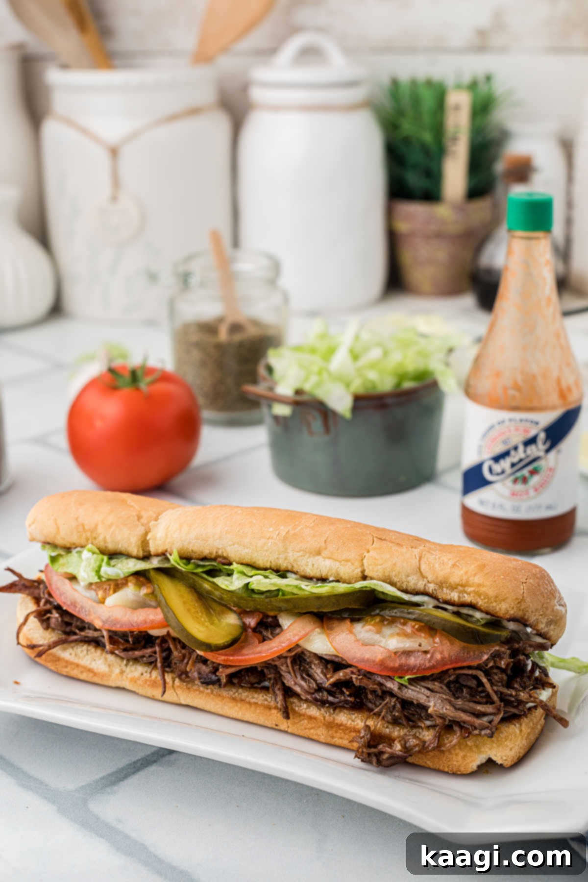 New Orleans Roast Beef Legend 9 Side view of a roast beef po boy with some hot sauce in the background.
