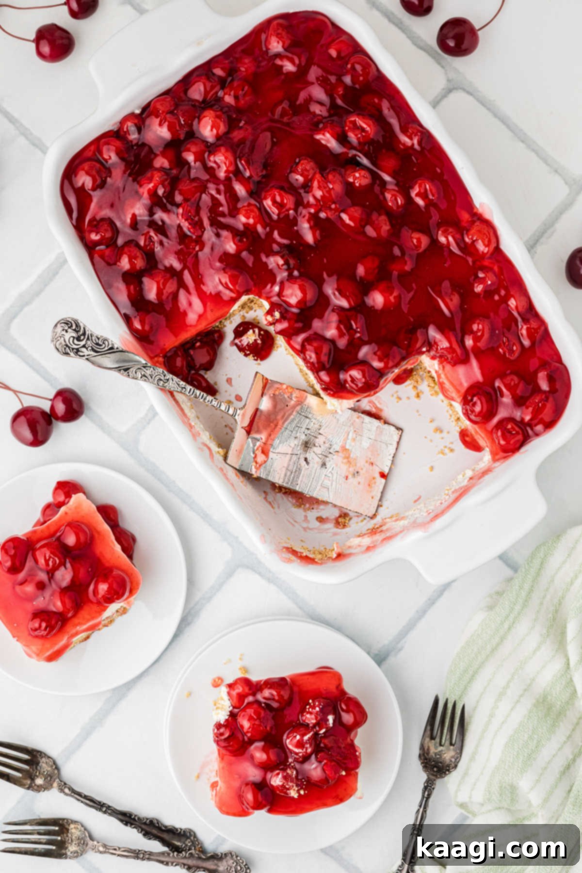 An overhead shot of a full dish of Old Fashioned Cherry Delight, with one slice perfectly plated on a white dessert plate beside it.