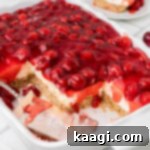 A dish with old fashioned cherry delight, with some squares missing and a spatula laying inside.