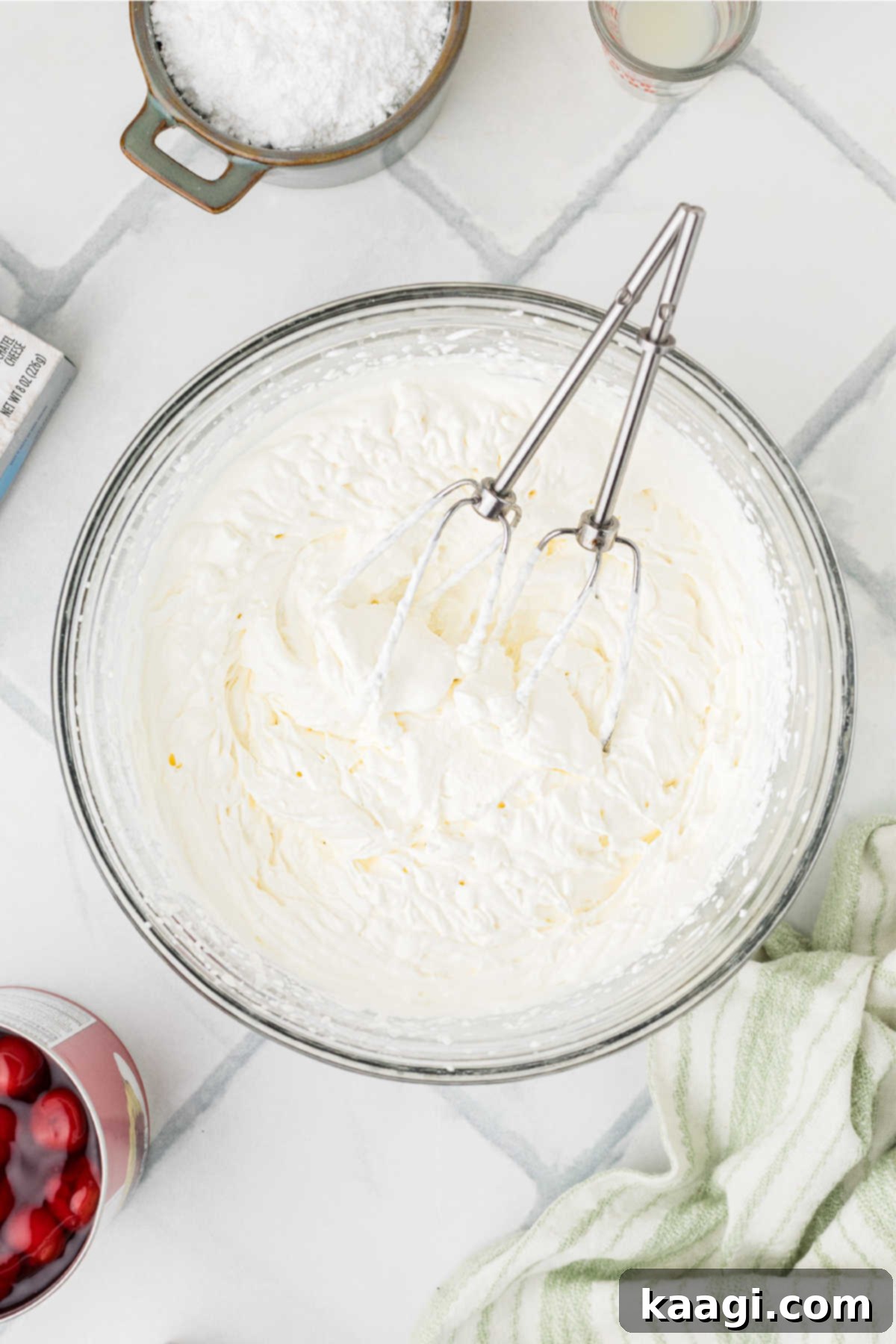 A large mixing bowl containing perfectly whipped heavy cream with stiff peaks.