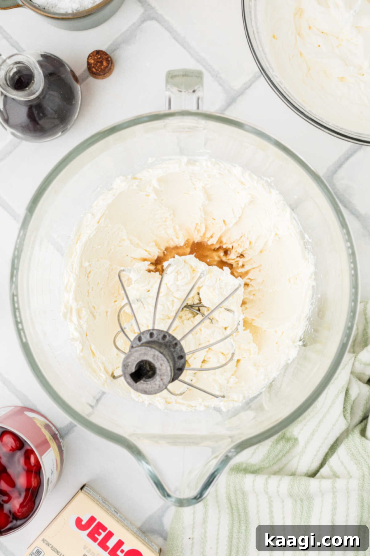 Whipped cream cheese being mixed with vanilla extract, vanilla pudding mix, and lemon juice in a stand mixer.