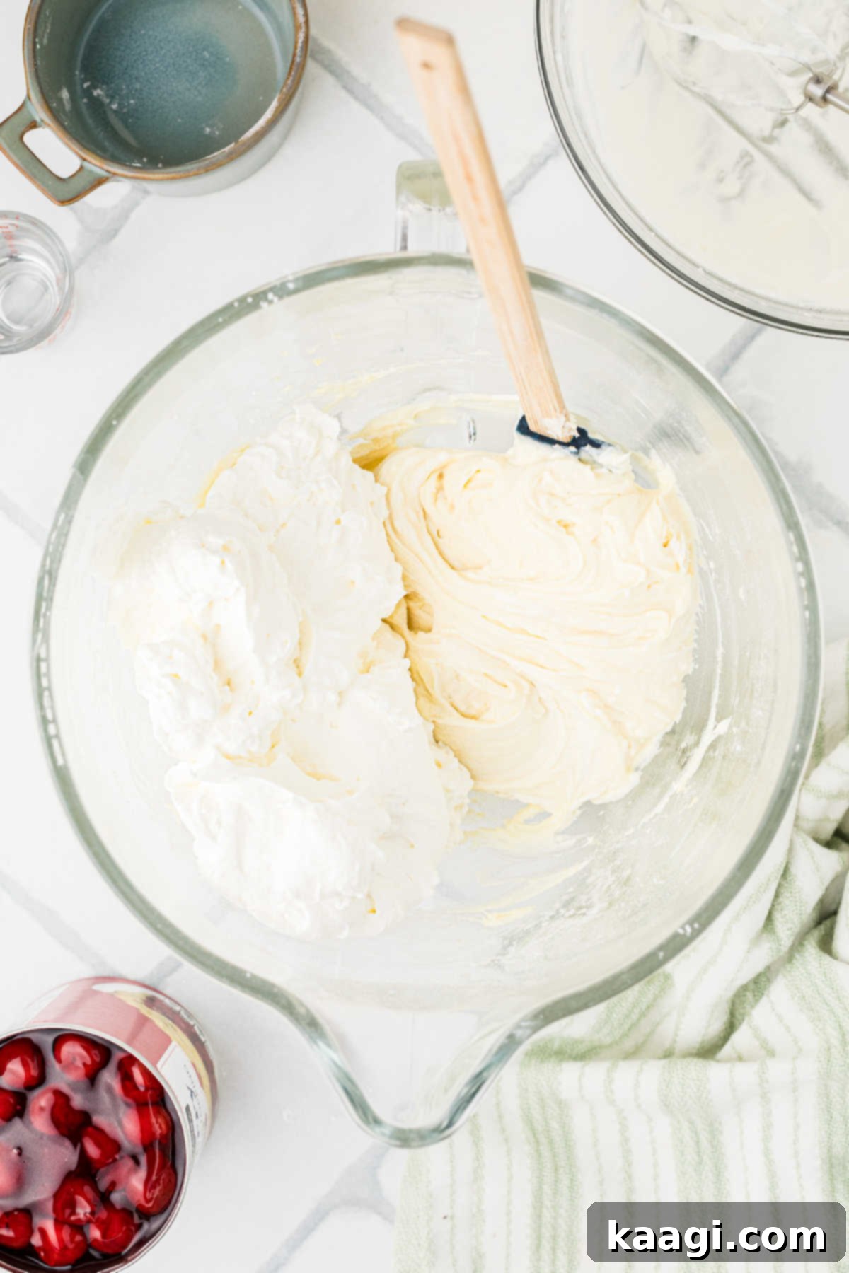 The previously whipped heavy cream being gently folded into the cream cheese mixture.