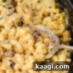 Close up of a spoon digging into a slow cooker cajun mac and cheese dish, highlighting the texture and richness.