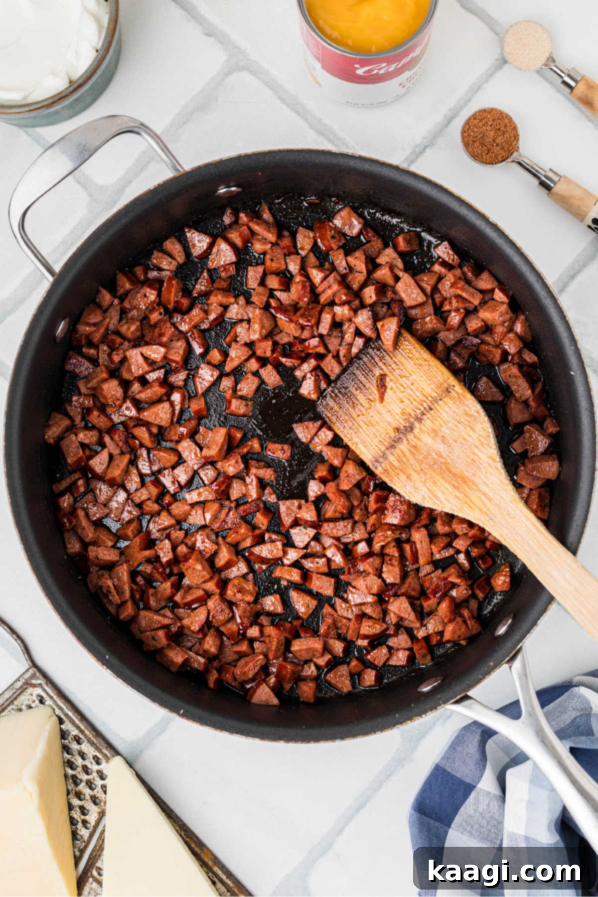 A large skillet with chopped andouille sausage sizzling and caramelizing, releasing its rich aromas.