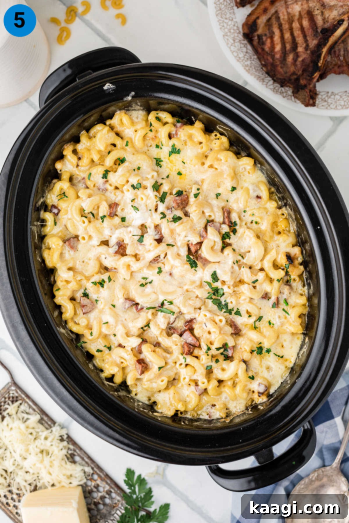 Overhead shot of a slow cooker filled to the brim with creamy Cajun mac and cheese, ready for the final cooking stage.