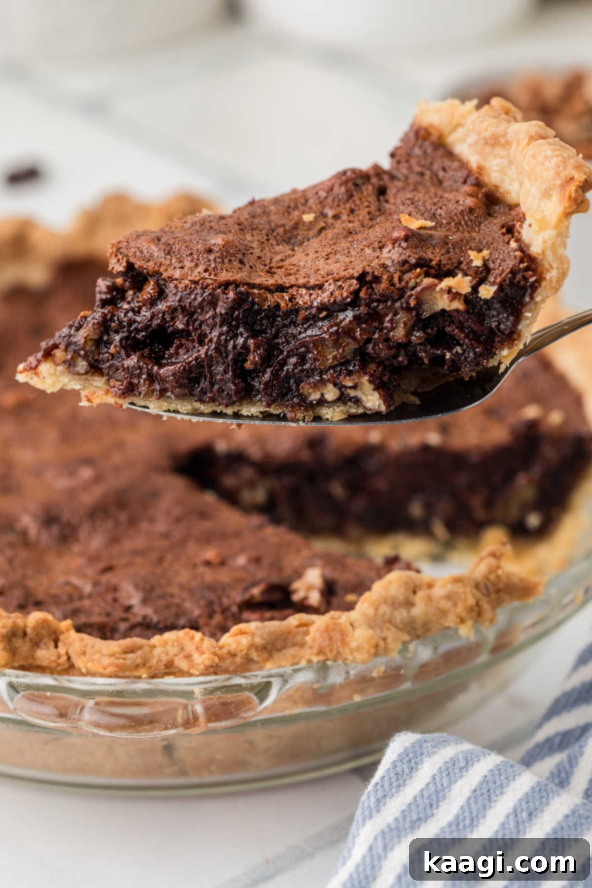 A delectable slice of homemade chocolate pecan pie, featuring rich chocolate and crunchy pecans, being carefully lifted from a pie dish, ready to be enjoyed.
