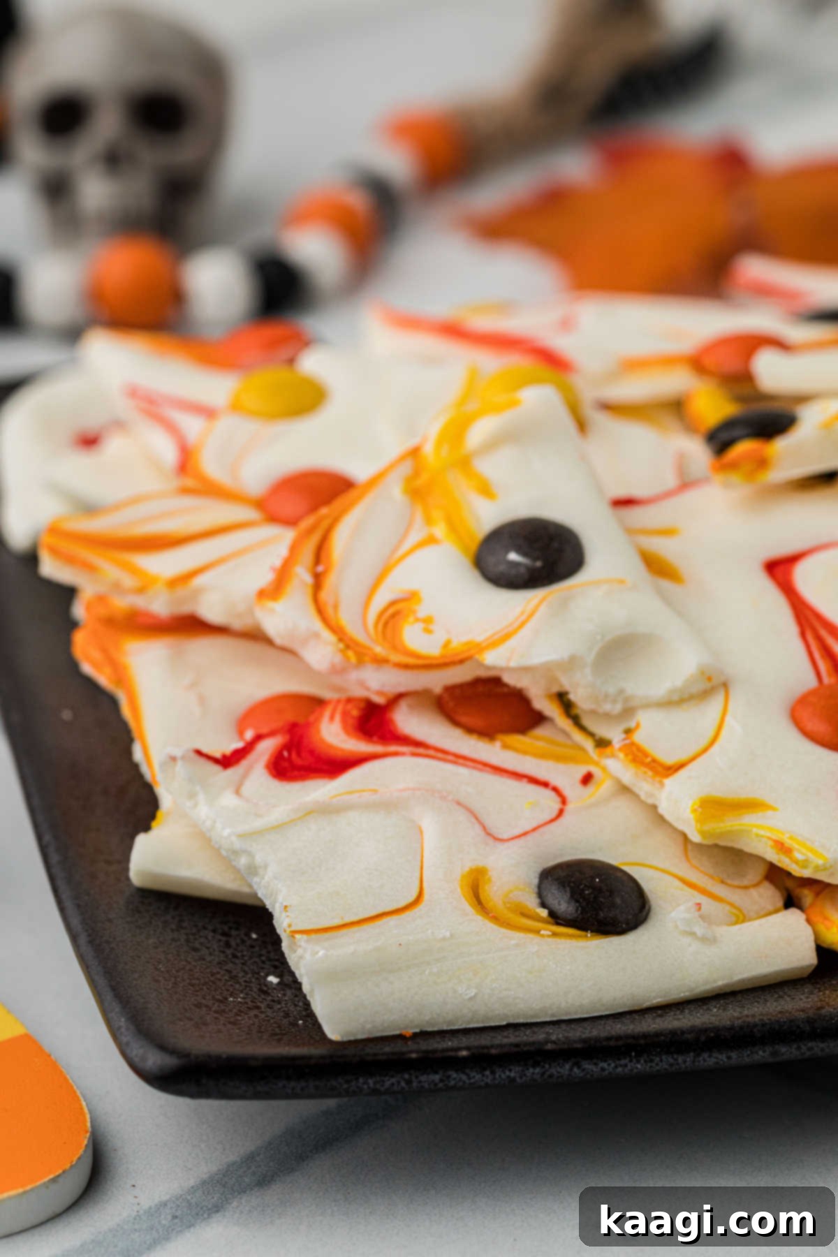 Creepy Crunch Bark 10 The corner of a plate full of Halloween bark, showing the vibrant colors and texture, ready for serving.