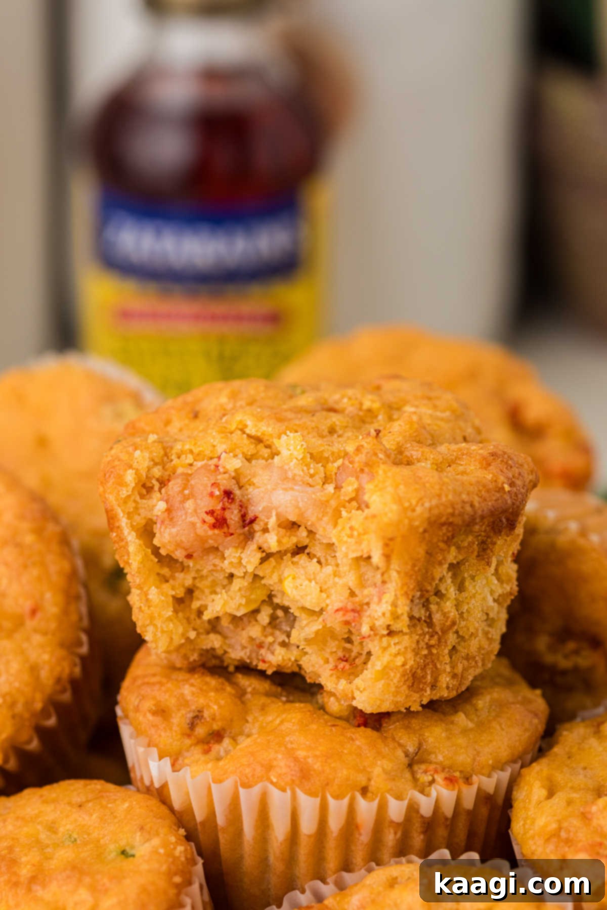 Cajun Crawfish Cornbread Muffins 2 A perfectly baked crawfish cornbread muffin with a small bite taken out, revealing its fluffy interior and succulent crawfish pieces, standing atop another golden-brown muffin, ready to be devoured.
