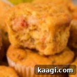 Cajun Crawfish Cornbread Muffins 13 A golden-brown crawfish cornbread muffin with a bite taken out, showcasing its fluffy texture and savory filling, resting on top of another muffin, signifying its readiness for enjoyment.