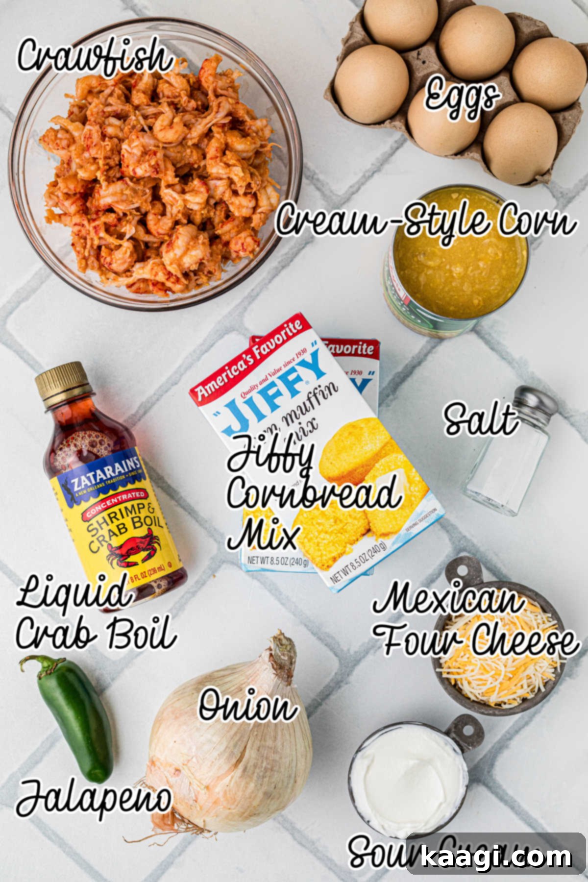 Cajun Crawfish Cornbread Muffins 3 A beautifully arranged flat lay of fresh ingredients on a light kitchen counter, featuring two eggs, a tub of sour cream, a can of creamed corn, two boxes of Jiffy cornbread mix, a bowl of shredded Mexican cheese, finely chopped onions, diced jalapeños, and a generous bowl of cooked crawfish tails. All components are neatly laid out, ready for preparation.