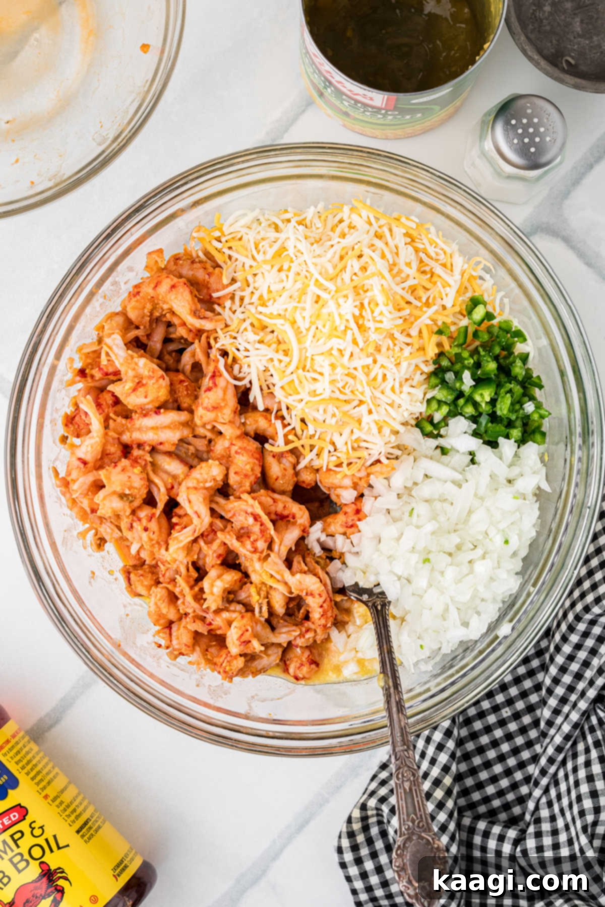Cajun Crawfish Cornbread Muffins 6 A generous quantity of chopped crawfish tails, a pile of shredded Mexican cheese, finely diced onions, and sliced jalapeños are carefully added on top of the wet ingredients in a large mixing bowl, ready to be gently folded in.