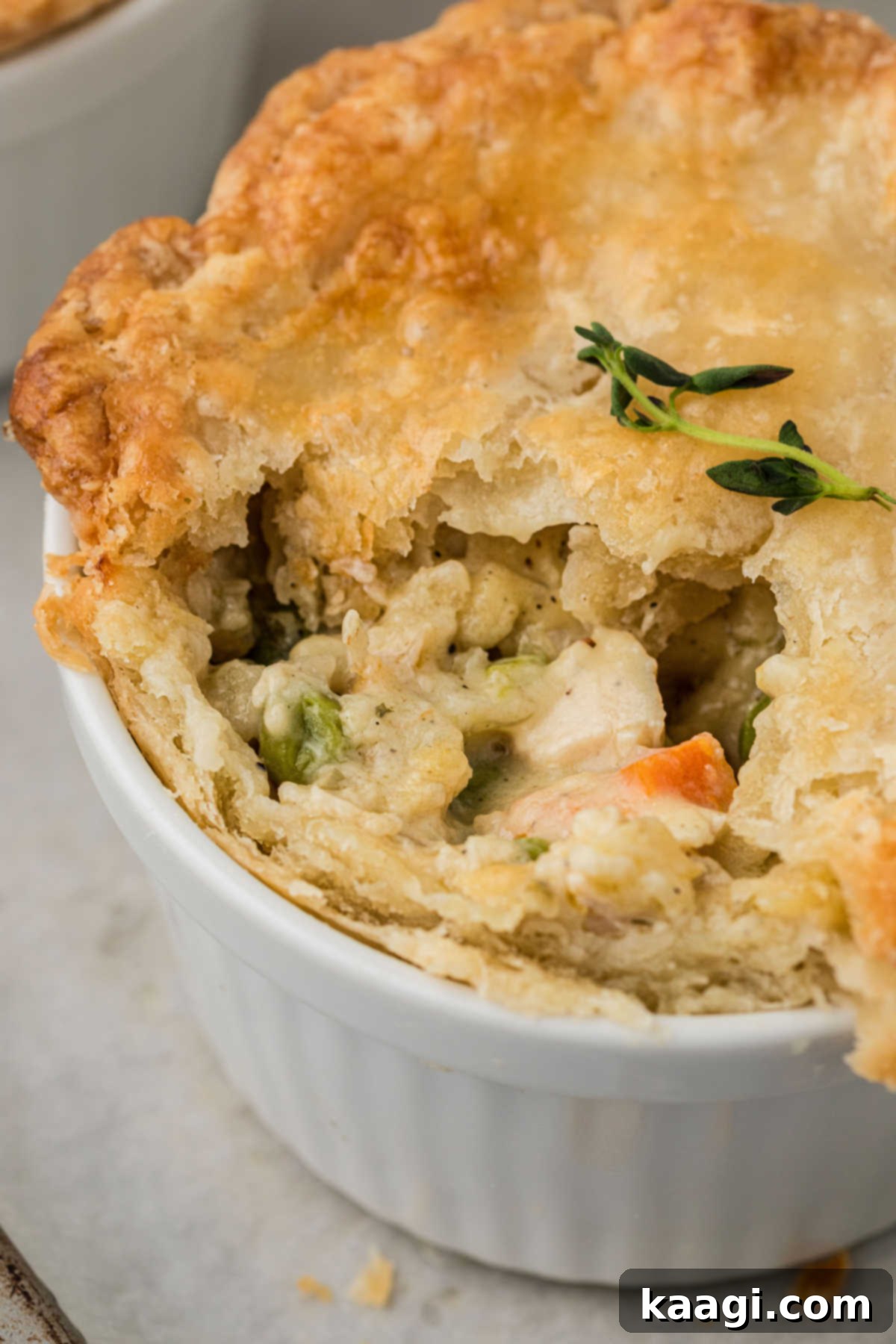 Comforting Mini Chicken Pot Pies 2 Close up shot of a mini chicken pot pie, with some missing, highlighting the flaky crust and creamy filling.