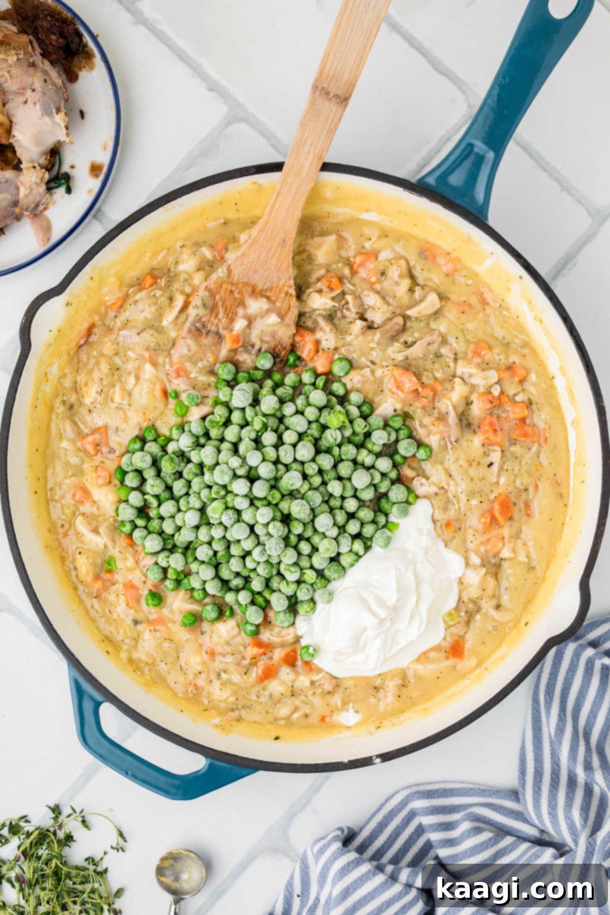 Comforting Mini Chicken Pot Pies 12 Frozen peas and sour cream added to the chicken pot pie filling, being stirred together.