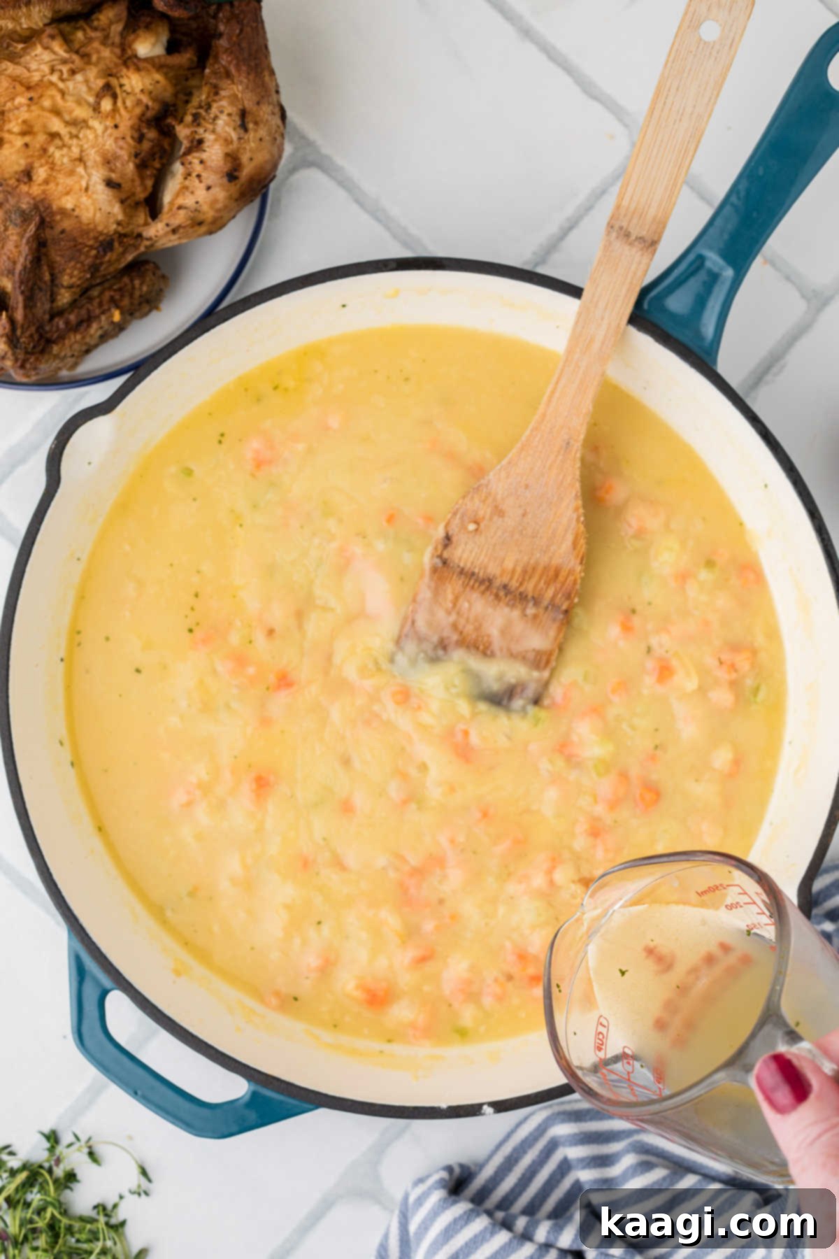 Comforting Mini Chicken Pot Pies 10 Chicken broth being slowly poured into a heavy bottomed skillet with the roux, while stirring.