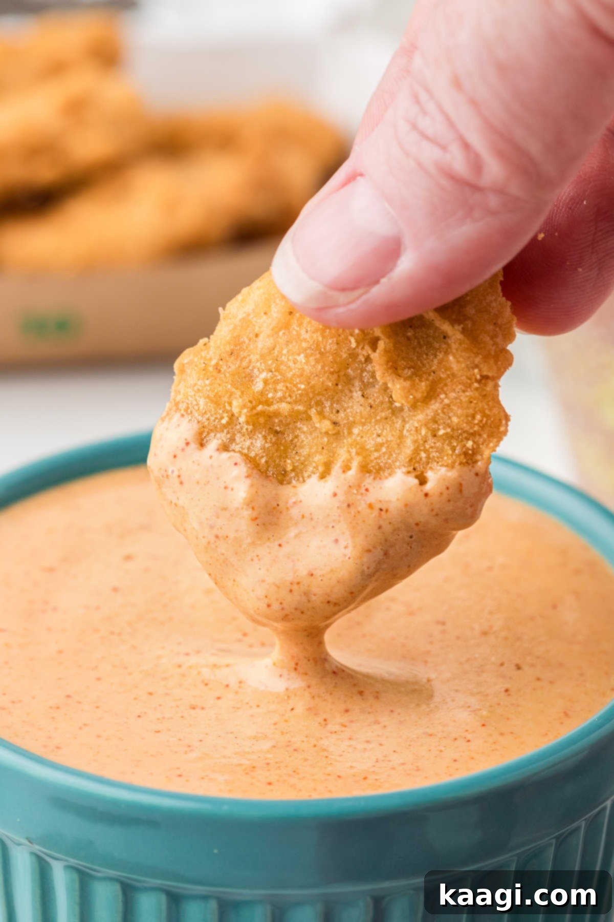A McDonald's chicken nugget being dipped into a Cajun Sauce.