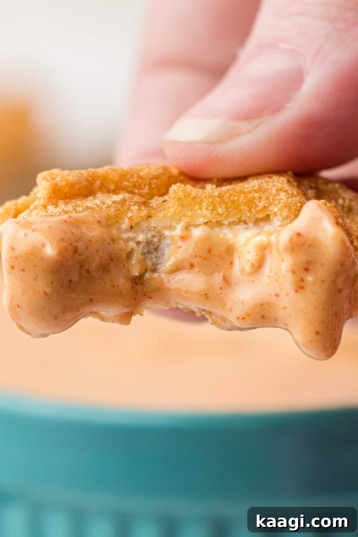 Close up of a chicken nugget that has been dipped in Cajun sauce.