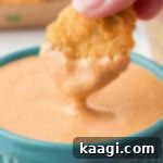 A McDonald's chicken nugget being dipped into a bowl of Cajun Sauce.