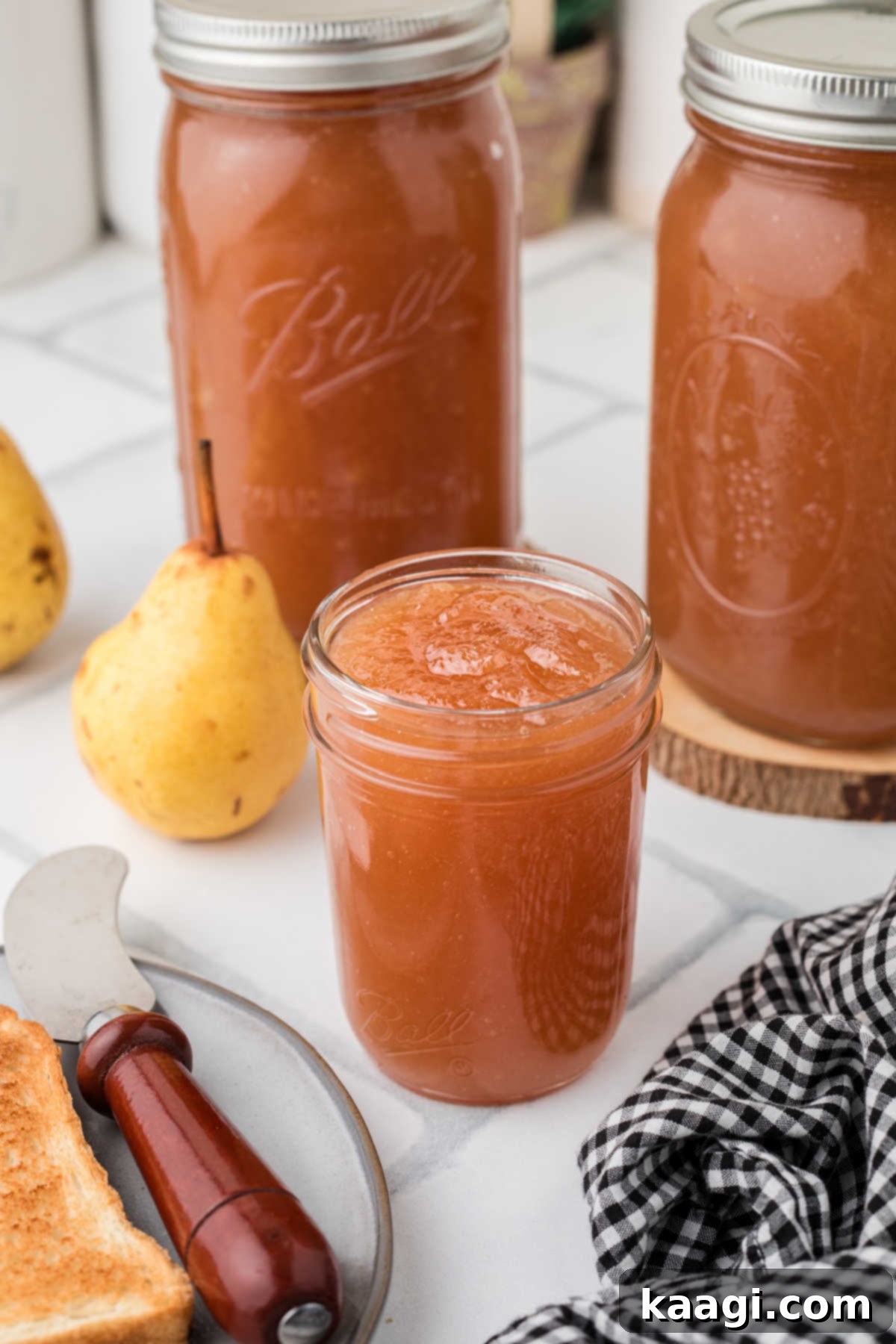 A jar of Amish Pear Honey, opened, about to be spread on a piece of toast, showcasing its beautiful texture.