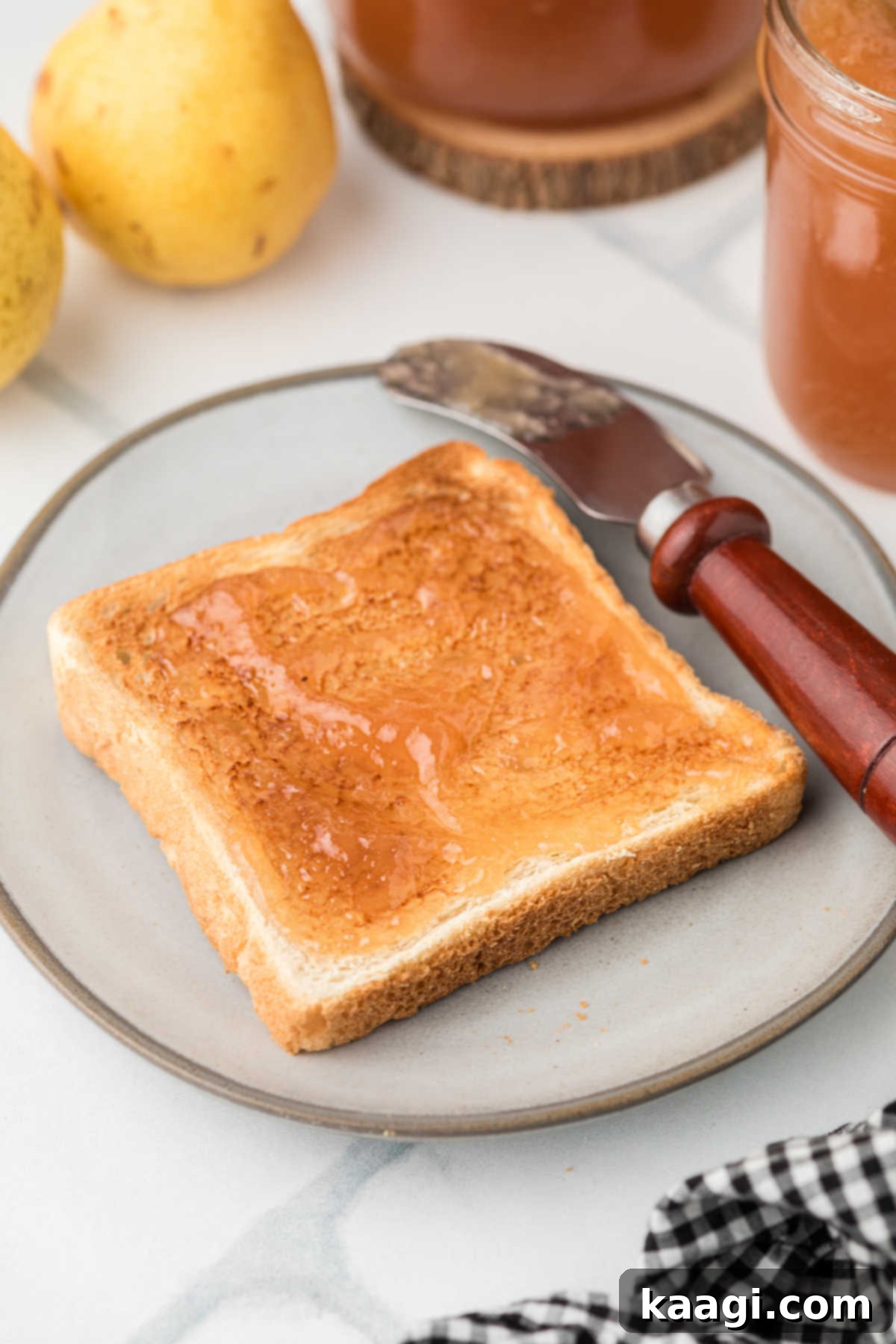 A piece of toast with some Amish Pear Honey spread on top, ready to be eaten.
