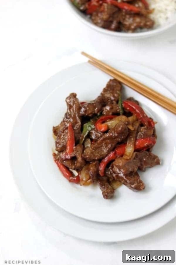 A single plate featuring Chinese Pepper Steak, adorned with colorful bell peppers and chopsticks.