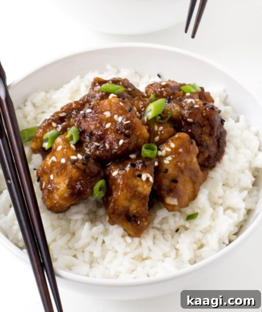 Slow Cooker General Tso's Chicken served on a bed of fluffy white rice, with chopsticks ready.