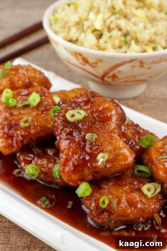 A close-up of beautifully sauced orange chicken, topped with vibrant green onions.