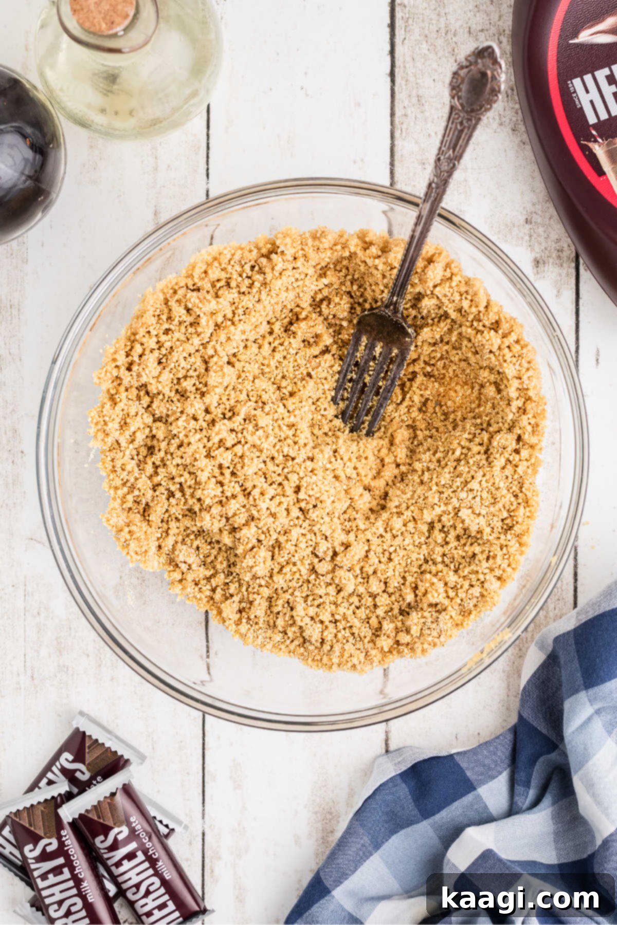 A large mixing bowl filled with golden graham cracker crumbs, melted butter, and sugar, ready to be mixed for the crust.