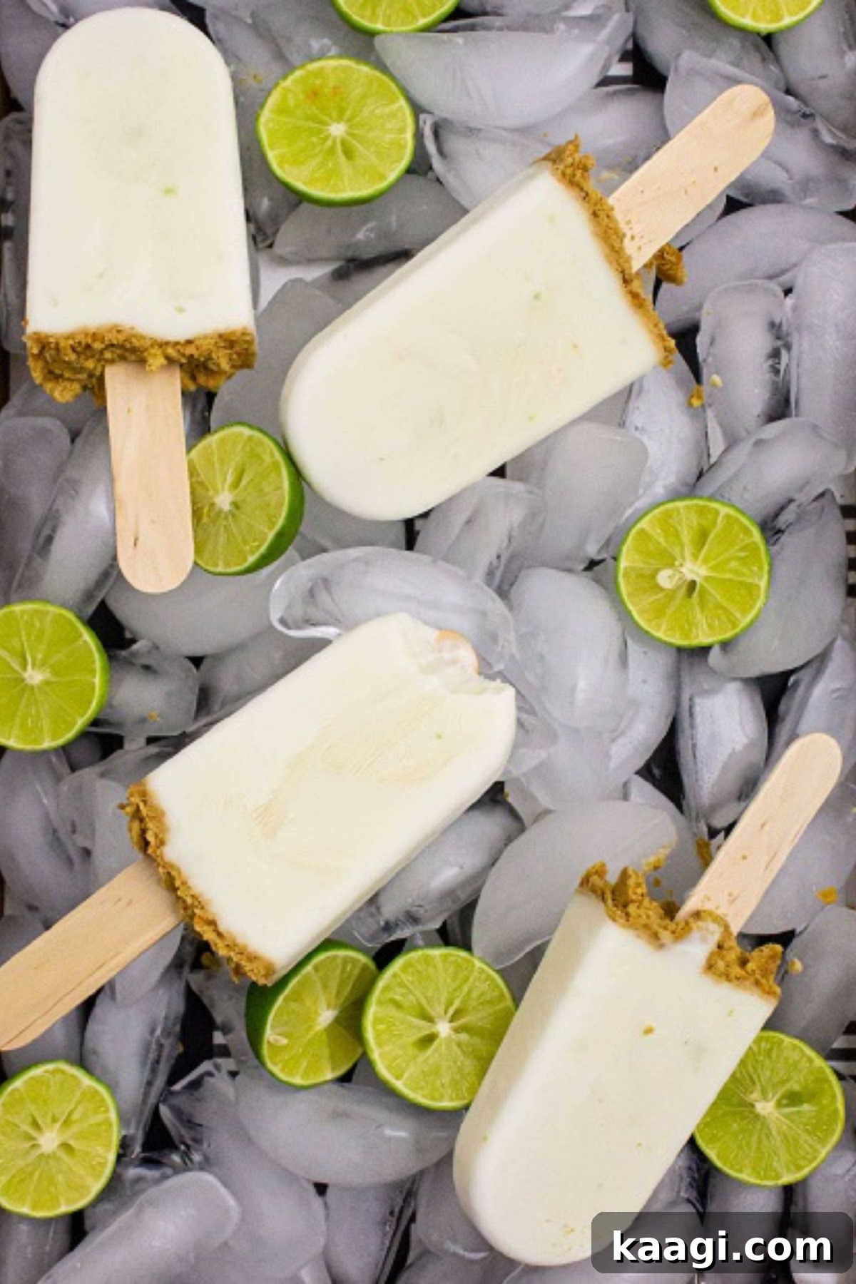 Zesty Key Lime Pops 2 Delicious Key Lime Pie Popsicles arranged beautifully on ice with scattered lime slices, one popsicle showing a bite taken out, highlighting its refreshing appeal.