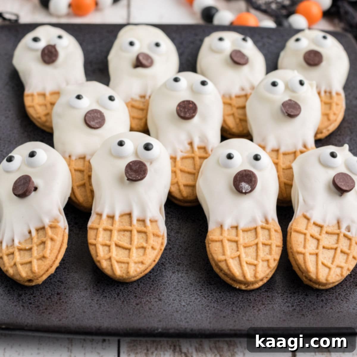 A close-up shot of a plate of Nutter Butter Ghosts, coated in white chocolate with candy eyes, perfect for Halloween.