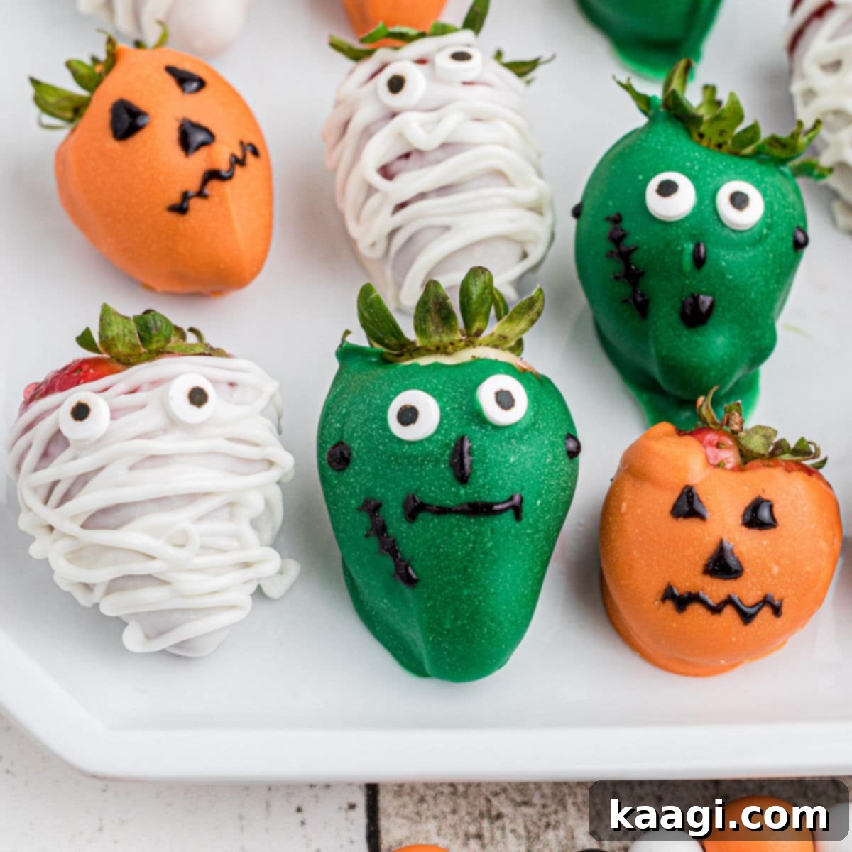 A close-up shot of several Halloween chocolate-covered strawberries, some decorated as ghosts or with spooky sprinkles.