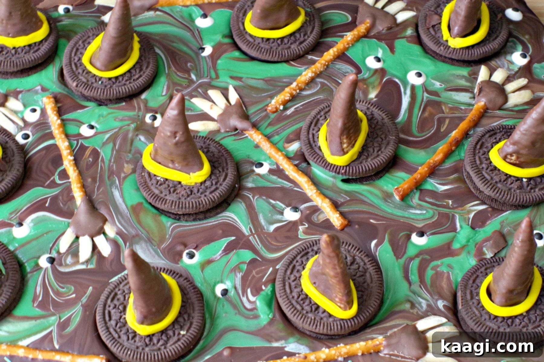 Vibrant Melting Witch Halloween Chocolate Bark, featuring dark and milk chocolate swirls, green candy melts, edible bugle hats, candy eyeballs, and pretzel brooms.