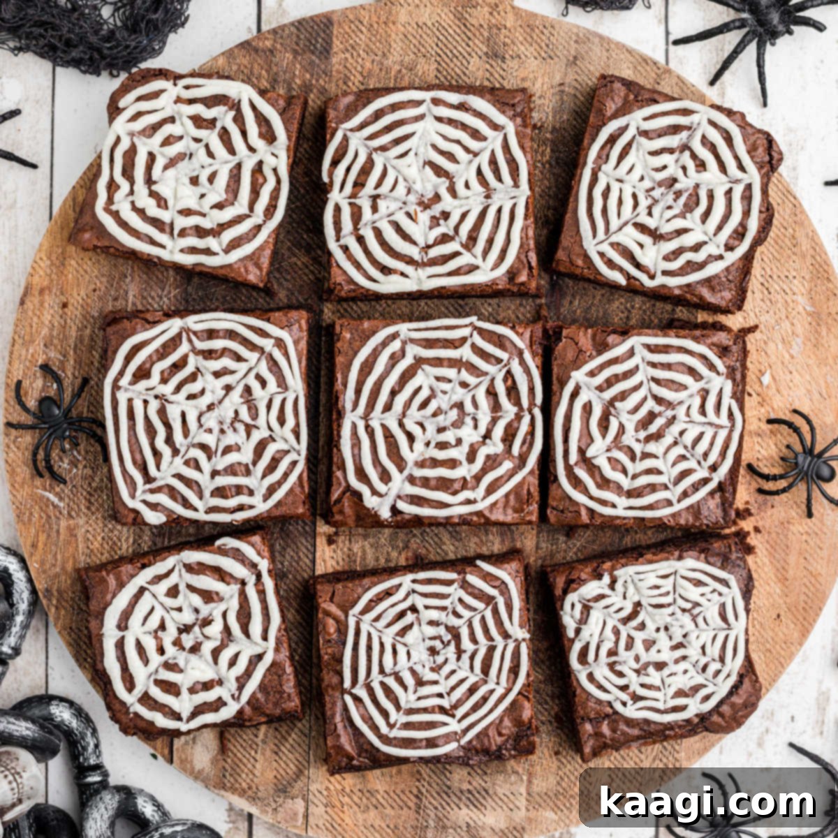 An overhead shot of a wooden board showcasing square spider web brownies, each topped with a delicate white icing web.