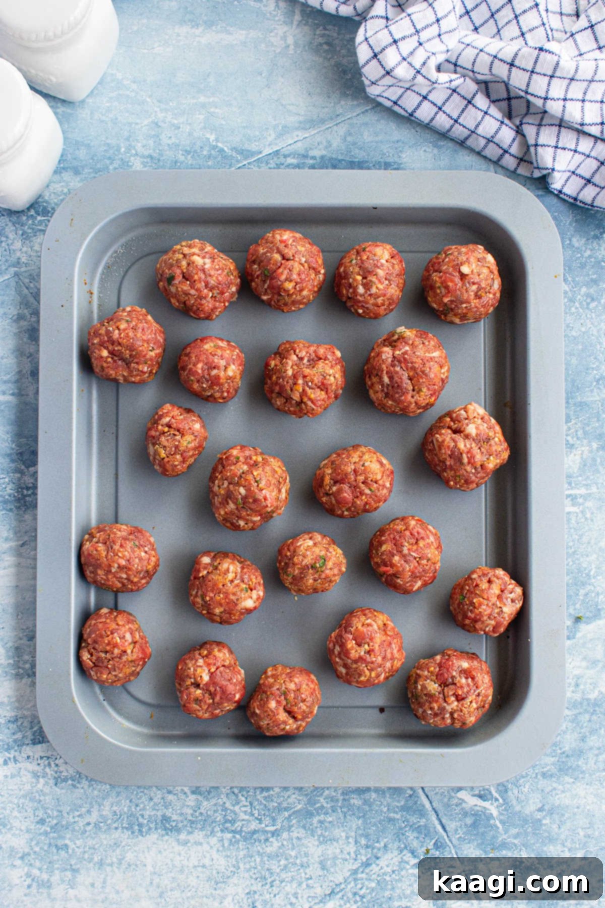 Several neatly formed meatballs arranged on a baking sheet, ready for browning.