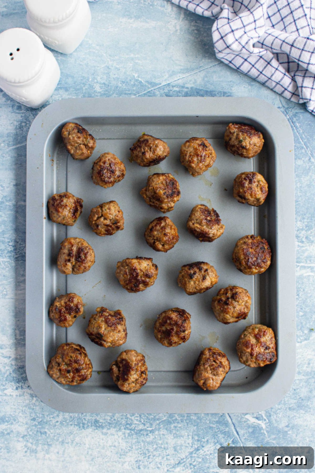 A baking sheet filled with perfectly browned meatballs, showcasing a delicious crust.
