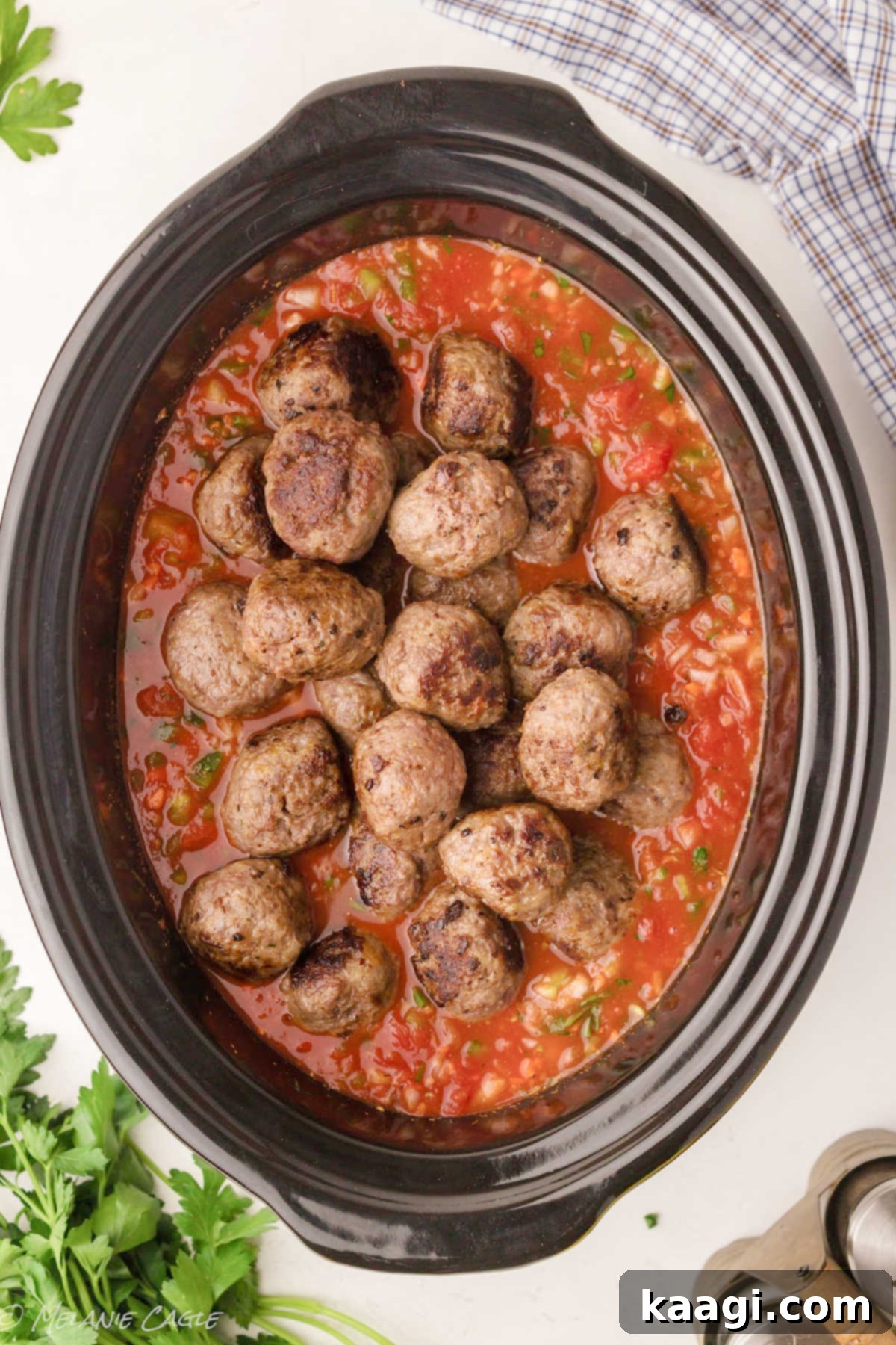 A large crock pot generously filled with a simmering sauce and perfectly browned meatballs.