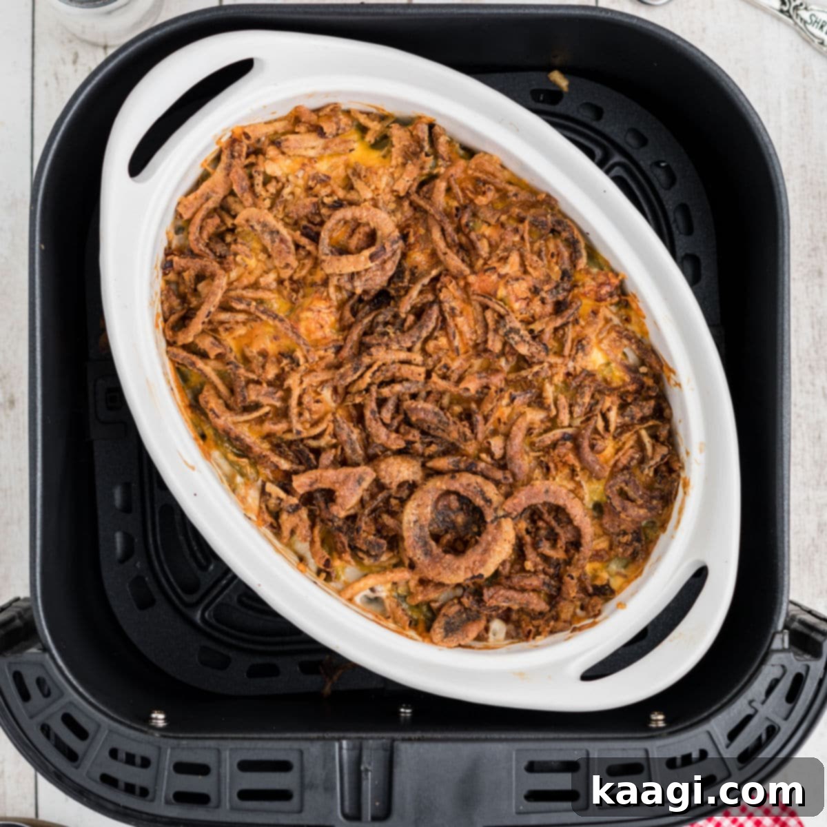 Overhead view of a golden-brown green bean casserole dish inside the basket of an air fryer.
