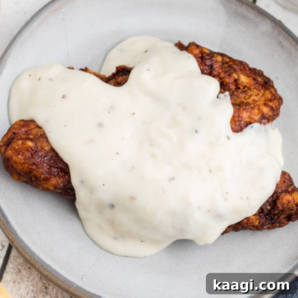 Overhead shot of creamy Southern white gravy generously poured over a pork chop.