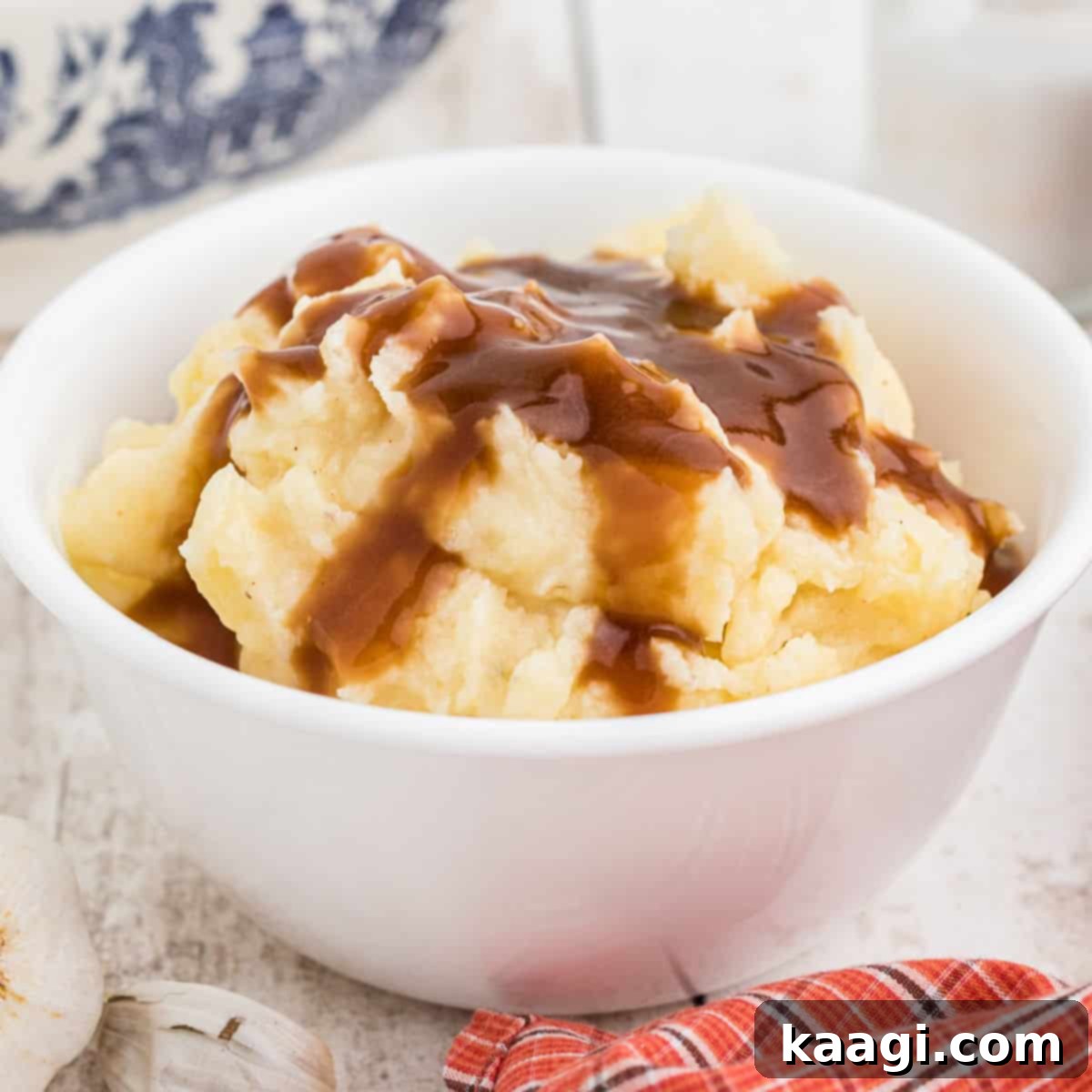 A hearty bowl full of creamy mashed potatoes with rich brown gravy on top, inspired by Popeyes.
