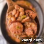 Close up of some pinto beans and sausage on a spoon over a crock pot.