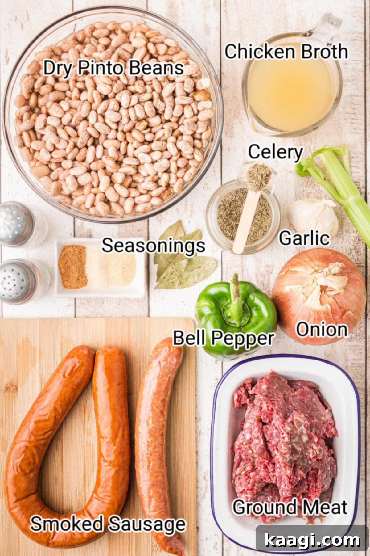 Ingredients for a savory crock pot pinto beans recipe, including dried beans, various sausages, and fresh vegetables, laid out on a kitchen counter.