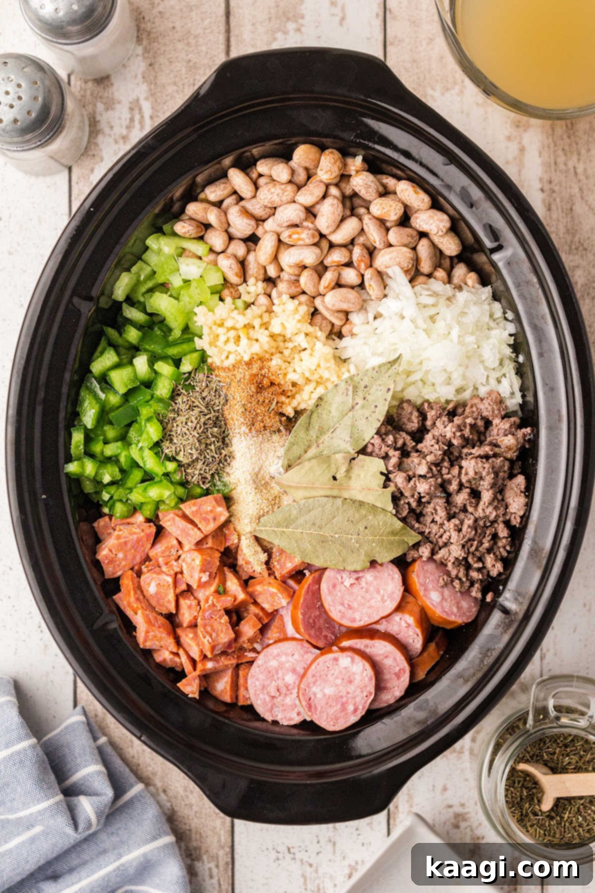 A crock pot filled with all the ingredients necessary for a hearty pinto beans recipe, ready for slow cooking.