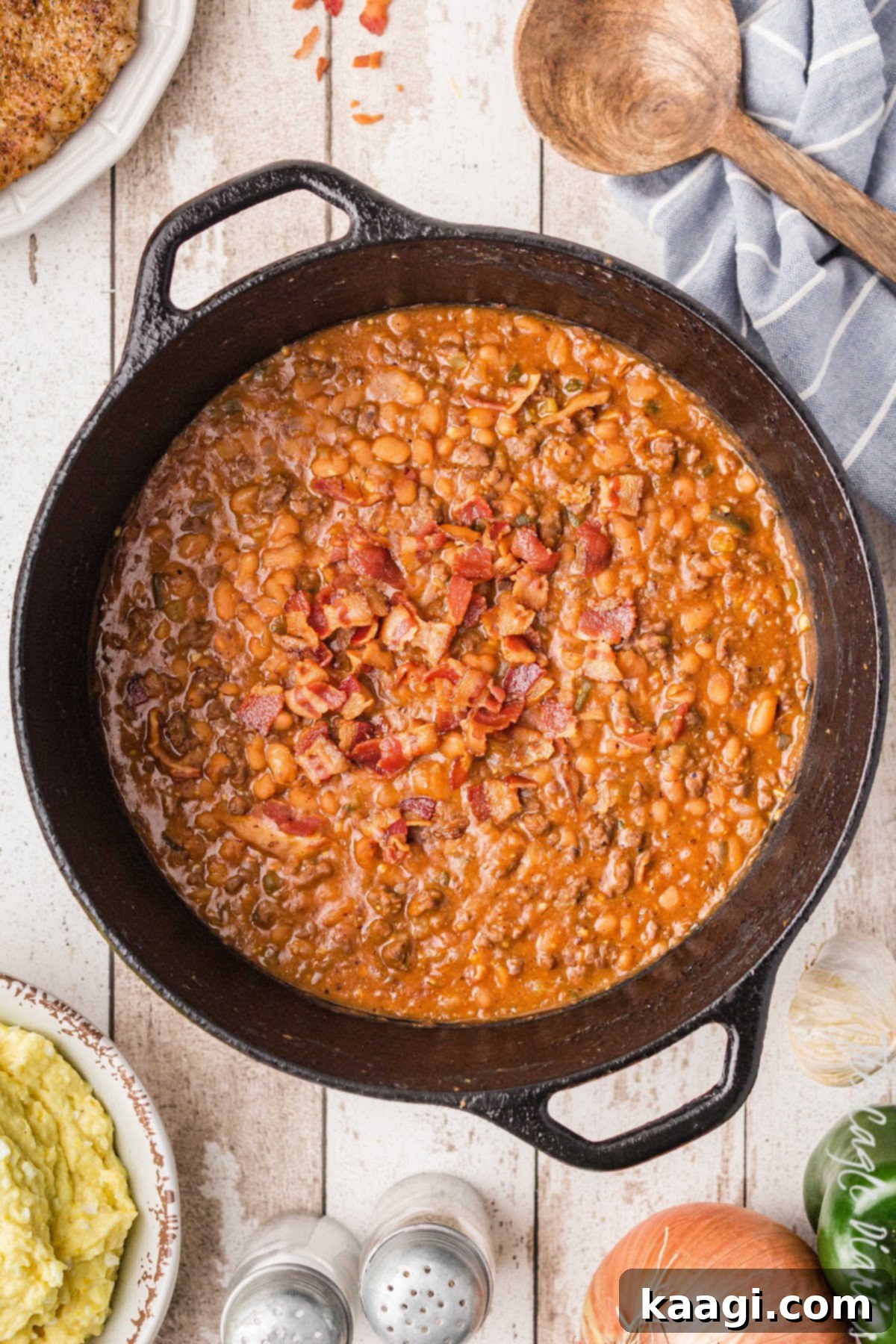 Soulful Southern Baked Beans 2 A big cast iron pot full of southern baked beans with some crispy bacon on top, ready to be served at a BBQ.