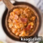 Soulful Southern Baked Beans 9 A close up of a spoon full of baked beans with crispy bacon, showcasing the rich texture and deliciousness.