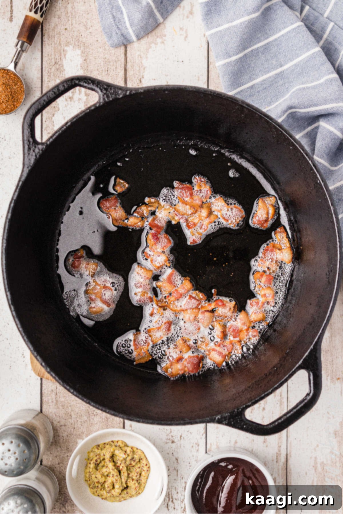 Soulful Southern Baked Beans 4 A cast iron pot with chopped bacon cooking, rendering its fat to create a flavorful base for the baked beans.