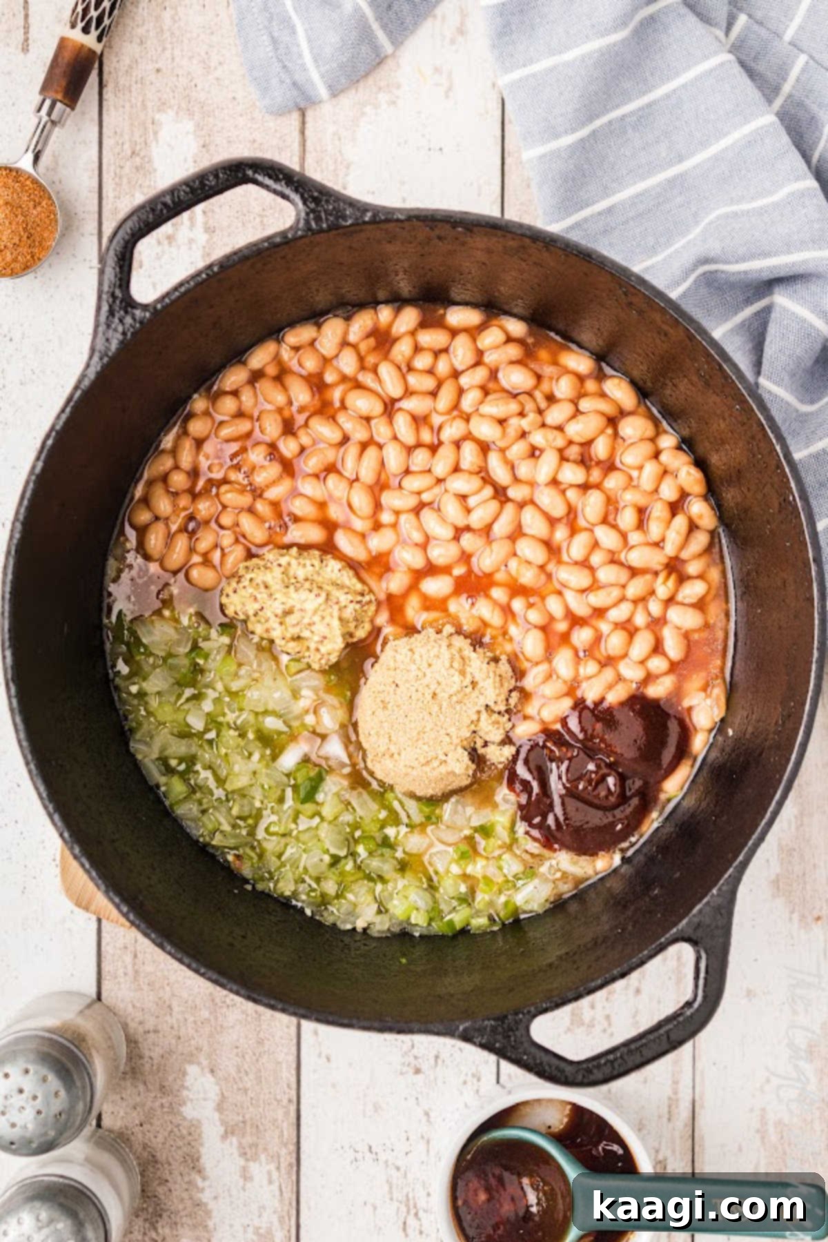Soulful Southern Baked Beans 6 A cast iron pot filled with baked beans, ground meat, and seasonings, stirred together before the slow cooking process begins.