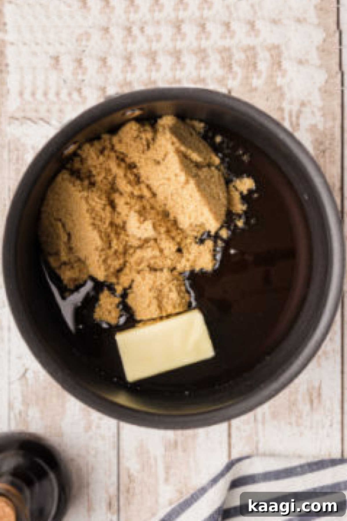 A saucepan on the stove containing butter, brown sugar, and corn syrup, gently melting together to form the base of the pecan pie filling.