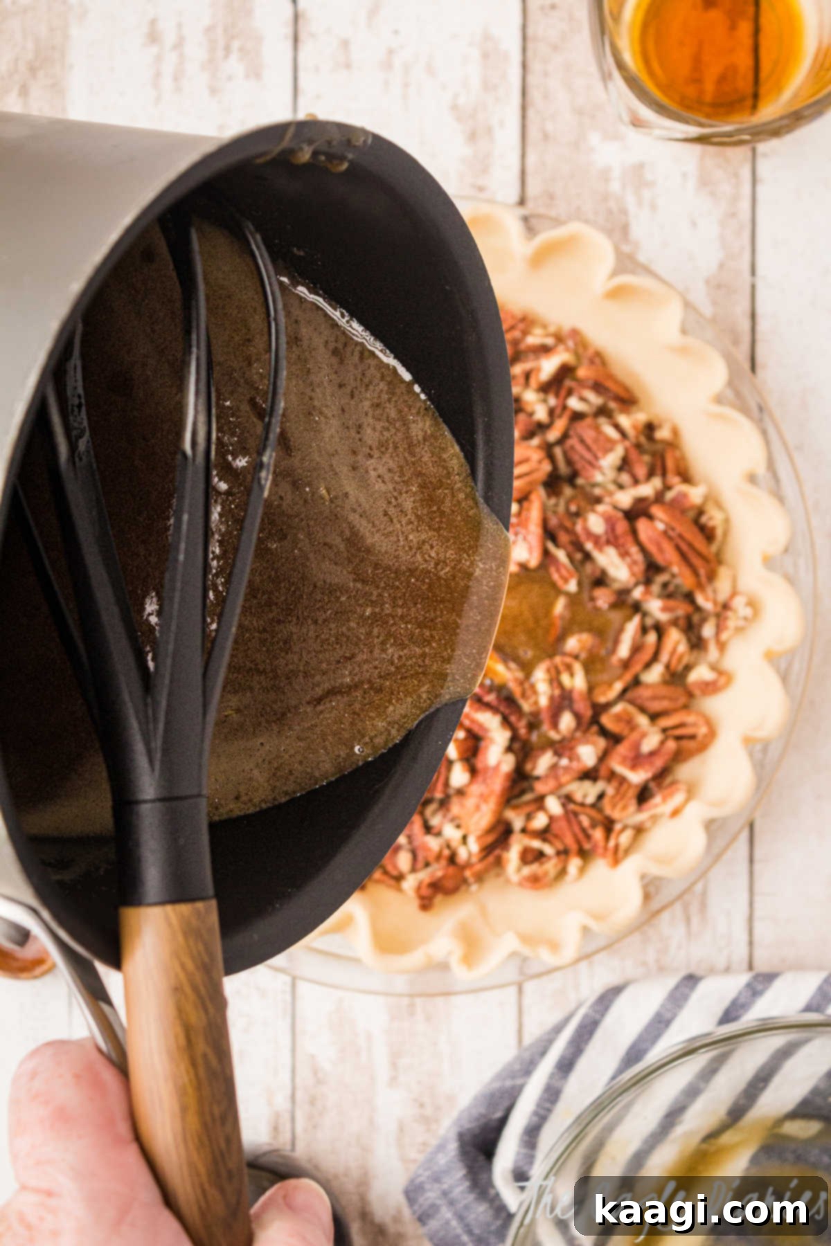 The glistening sugar and butter mixture being carefully poured over the bed of pecans in the pie crust, ready to create the rich pecan pie filling.